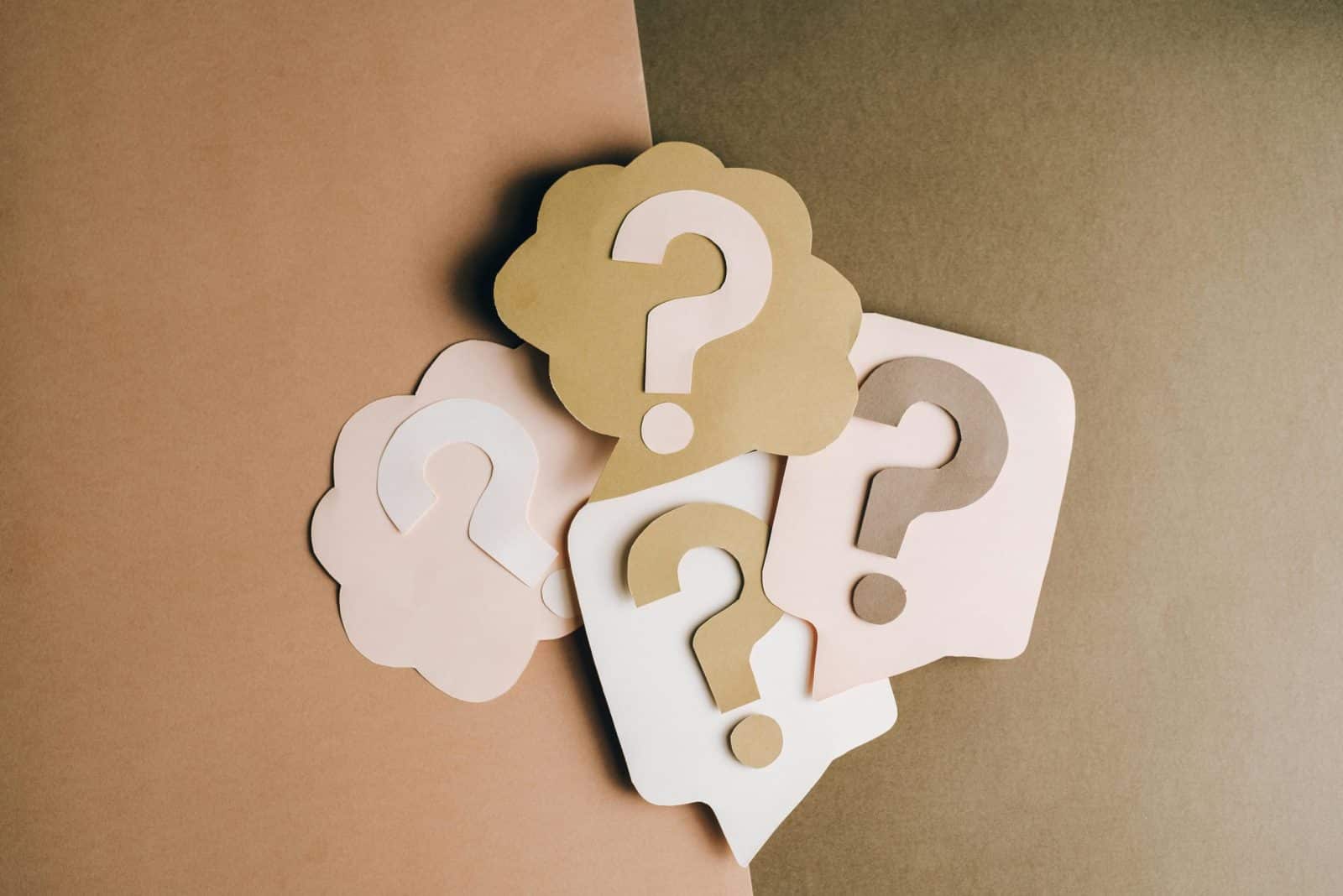 Good investment. Question mark cutouts in layered paper craft style on a brown backdrop, conceptual art.