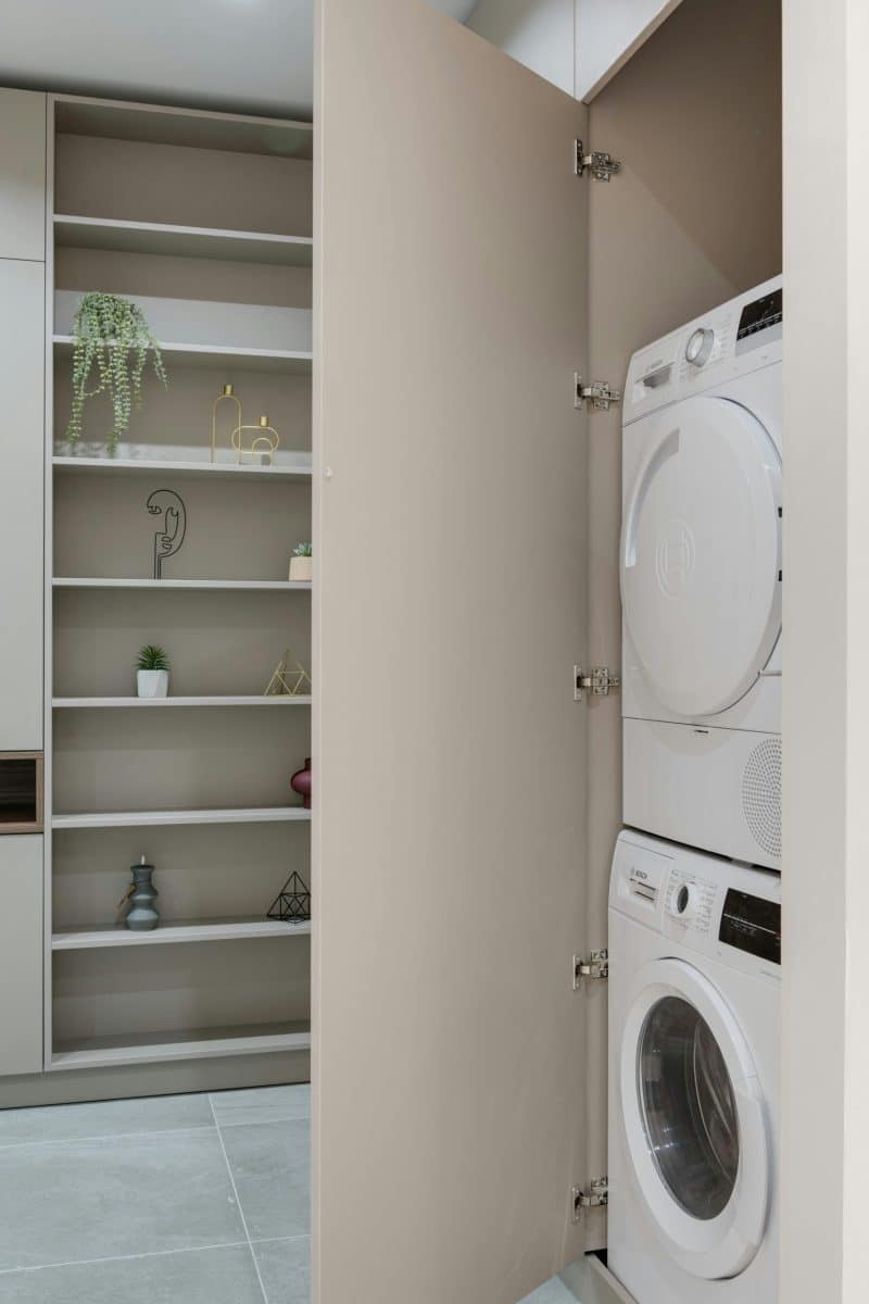 A stylish laundry area featuring stacked washer and dryer within a hidden cabinet.